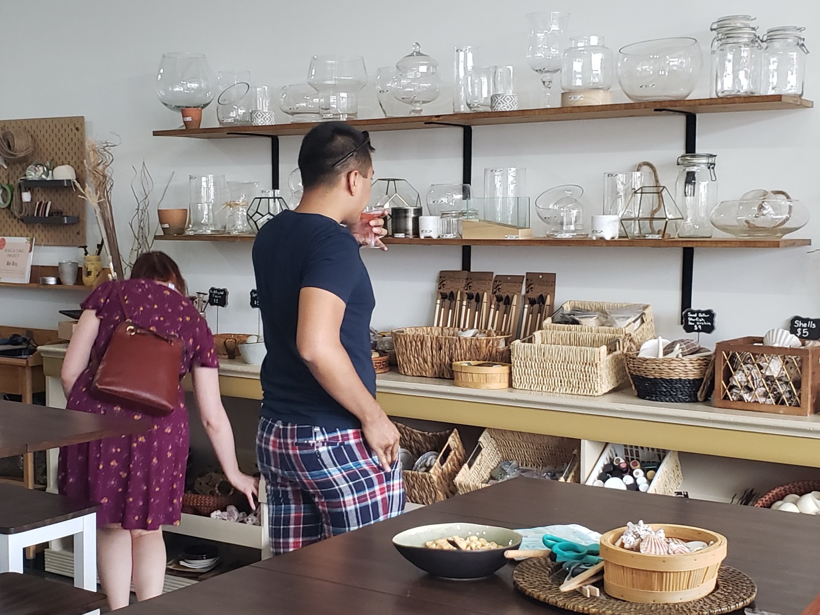 Two customers browsing the vessel shelves and supply bins inside the studio
